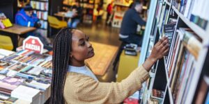 beautiful-university-student-reaching-books-on-upper-shelves-in-the-library.jpg