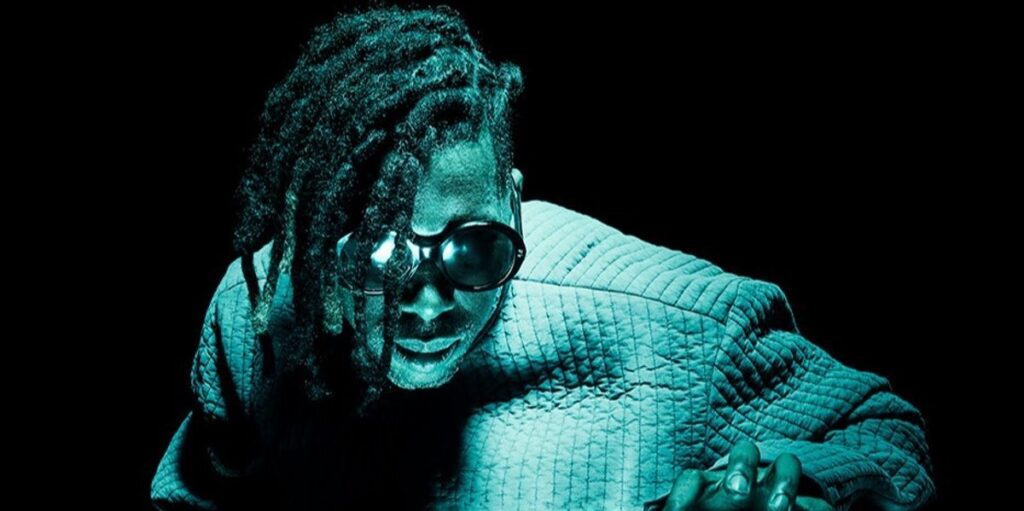 flying-lotus-in-water-up-to-his-chest-with-dreads-and-glasses.jpg