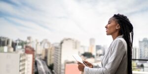 a-black-womaln-holding-an-ipad-looks-out-over-the-city-smiling.jpg
