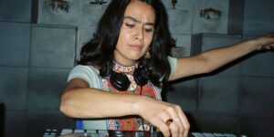 a-woman-with-headphones-aroun-her-neck-twists-nobs-on-a-dj-table.jpg