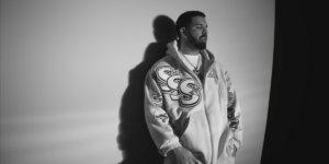 drake-leans-againsta-wall-in-black-and-white-wearing-a-chain-and-a-letterman-s-jacket.png