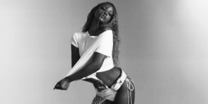 justine-skye-poses-for-a-photo-in-a-white-top-and-leather-cowgirl-shorts.png
