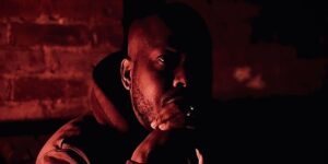 errol-eats-everything-poses-for-a-photo-with-a-hoodie-on-in-a-dark-room-with-a-red-tint.jpg