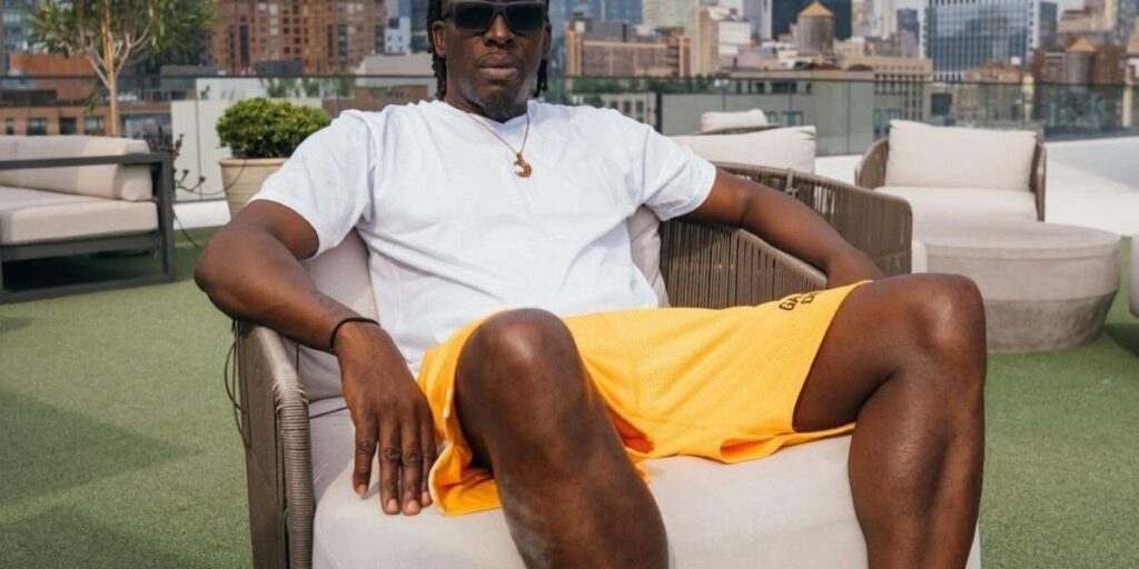saleem-gyau-in-a-white-shirt-and-colorful-shorts-lounges-in-a-chair-with-the-new-york-city-skyline-in-the-background.jpg