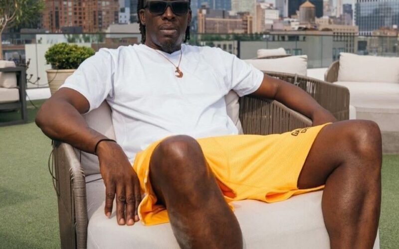 saleem-gyau-in-a-white-shirt-and-colorful-shorts-lounges-in-a-chair-with-the-new-york-city-skyline-in-the-background.jpg